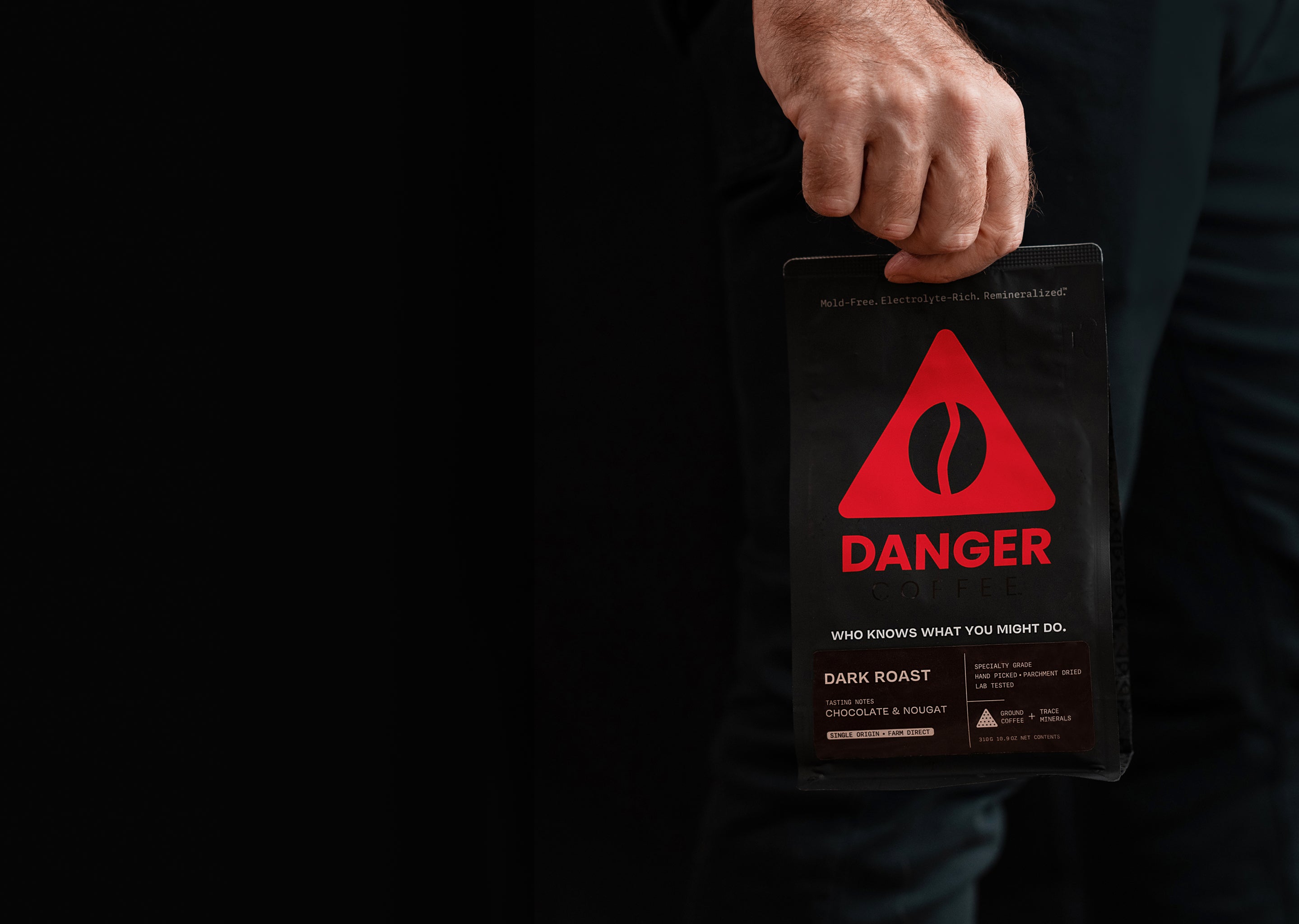 Hand of a man holding a Danger coffee bag with red triangle logo