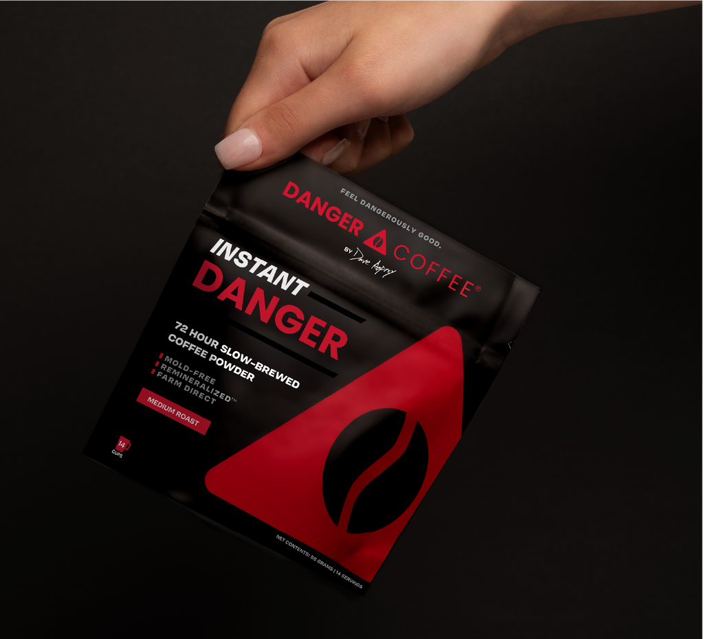 Instant Danger coffee package held by a hand on a black background