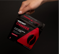 Instant Danger coffee package held by a hand on a black background