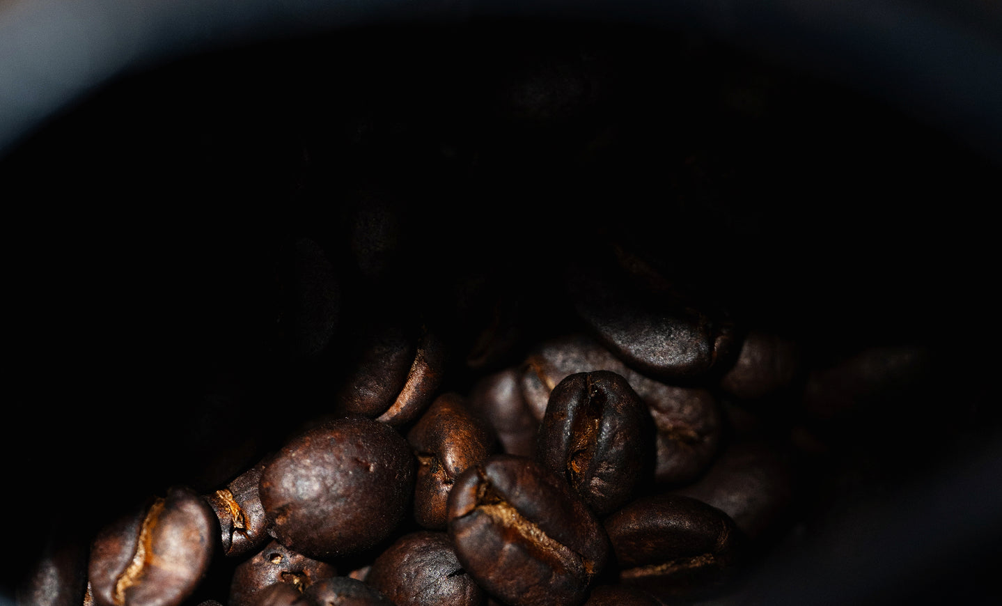 Close-up of Danger Coffee beans spilling from bag onto rustic wooden table surface.